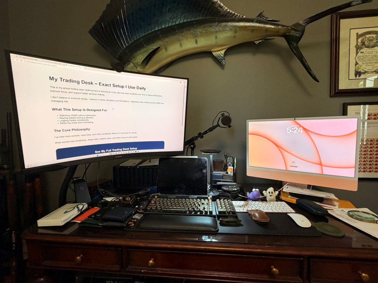Close view of Greg Cook's trading desk with monitor, keyboard, iMac, microphone, desk pad, and trading tools