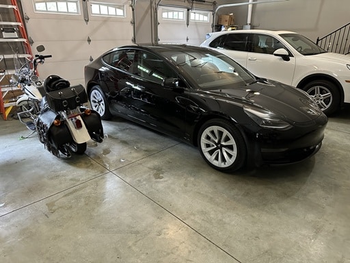 2023 Tesla Model 3 pictured with Harley and Porsche in Greg's garage